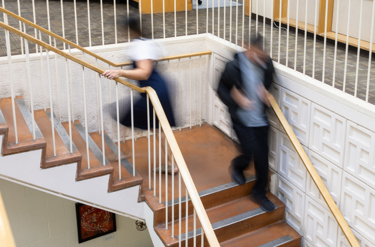 two blurred people walking up and down library stairs