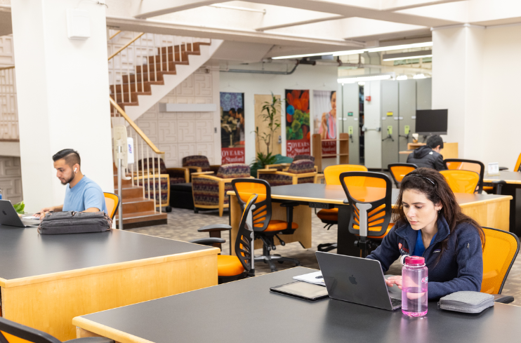 students studying at tables on the ground floor of the library